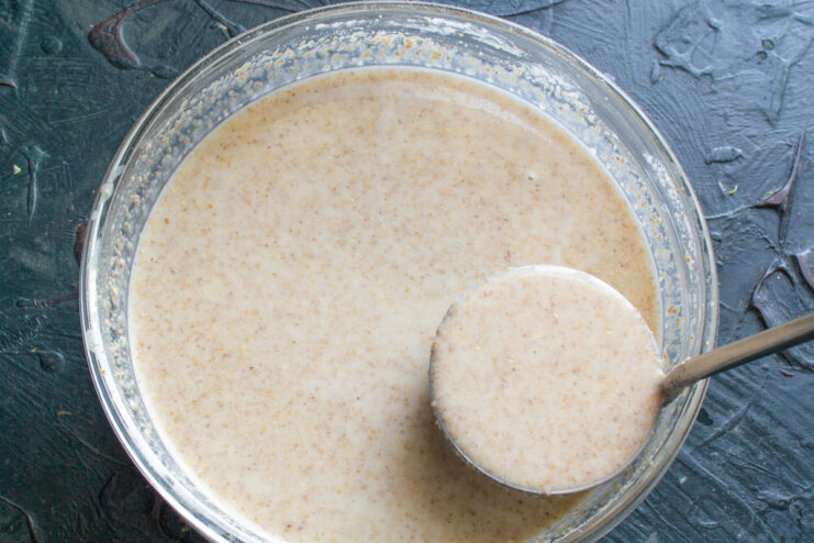 Preparing to fry Small ladle holding a portion of batter over a mixing bowl