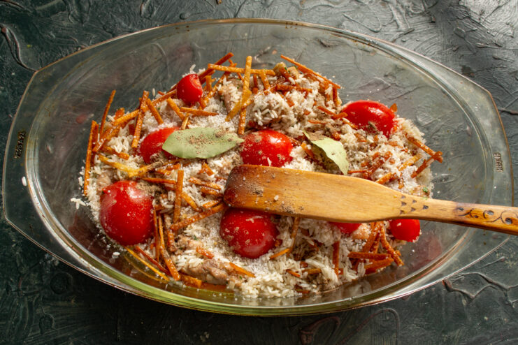 Arranging small tomato halves and bay leaves on top of the rice layer