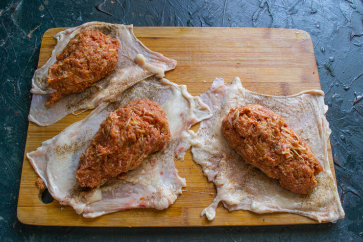 Portioning The Sausage Meat Equal portions of ground beef filling placed on prepared chicken skins