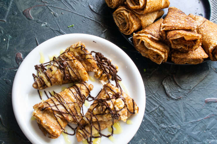 Final crepe decoration Portion of crepes generously drizzled with chocolate glaze and topped with walnuts