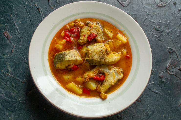 Top-down view of a hearty portion of fish solyanka served in a deep bowl.