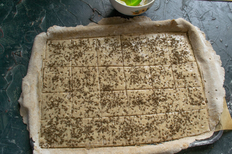 Adding caraway seeds Sprinkling caraway seeds over the unbaked scored dough