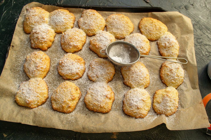 Dusting with powdered sugar Dusting freshly baked coconut cookies with powdered sugar through a sieve