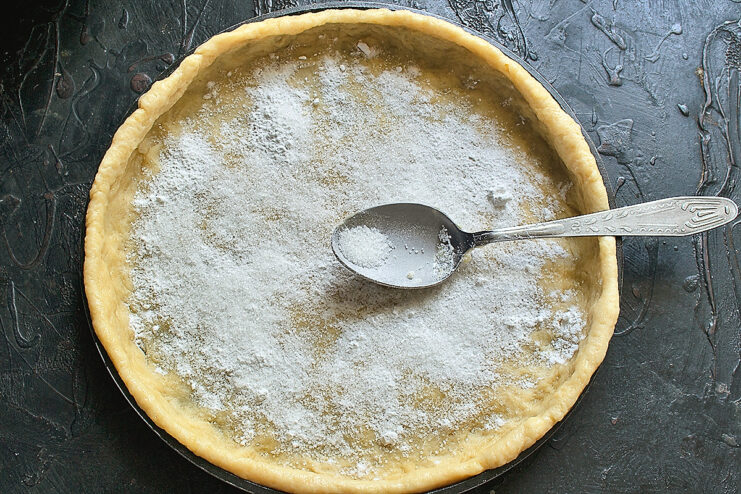 Sprinkling starch over the dough. Dusting the rolled dough with a layer of potato starch and sugar