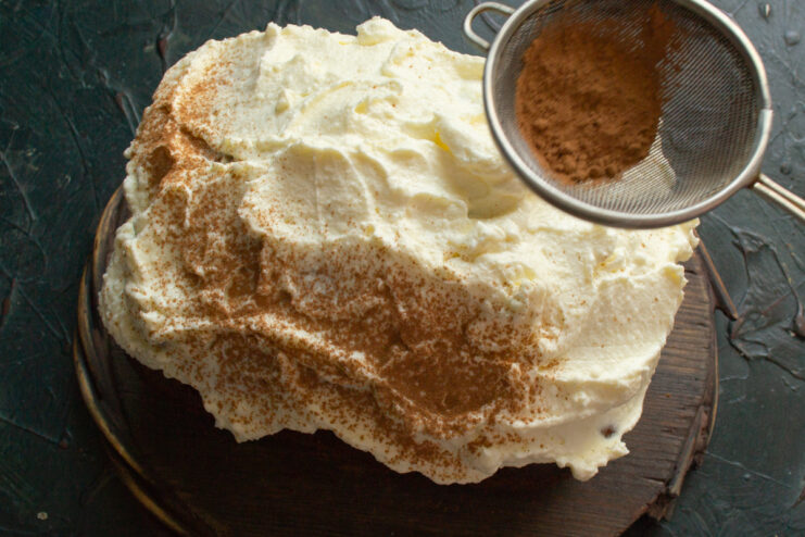 Decorating with cream Dusting cocoa powder over the thick whipped cream on the cake