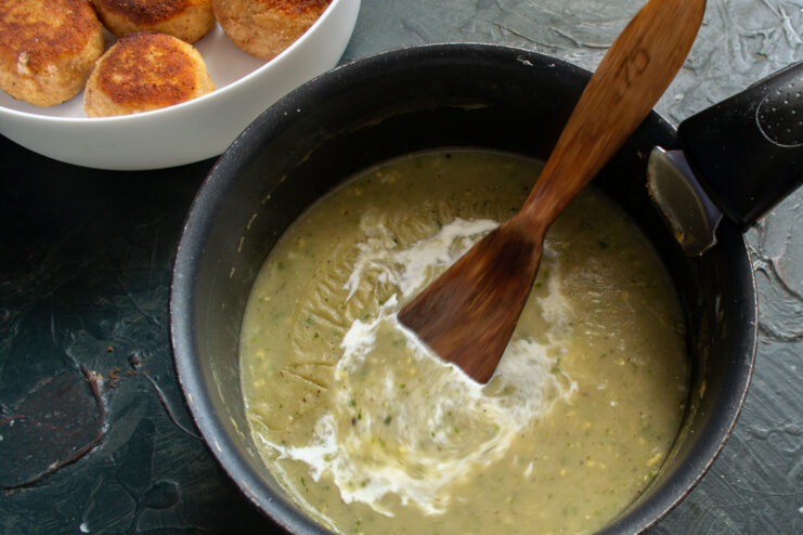 Cooking creamy sauce with herbs in a saucepan
