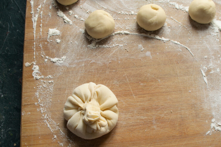 Pleating the edges of thin dough to shape a khinkali