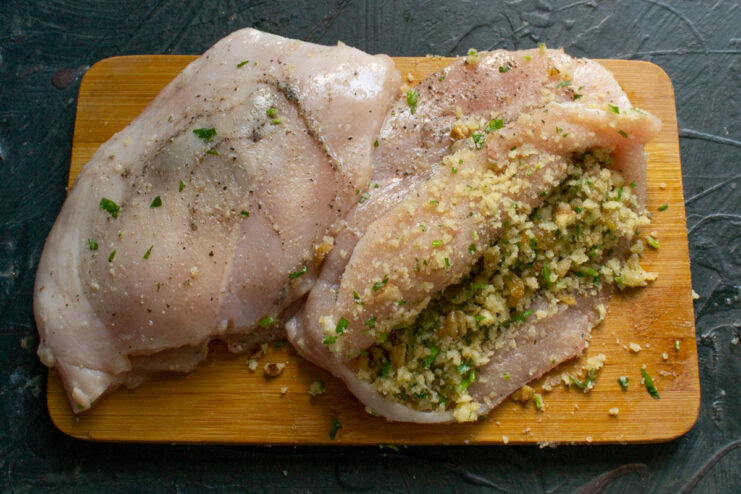 Stuffing the pocket with the prepared filling Chicken breast pocket being tightly packed with the walnut, raisin, and cheese filling.