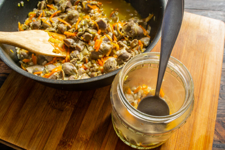 Packing stew into jars Filling a glass canning jar with gizzard and pearl barley stew