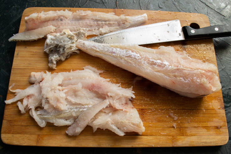 Separating fish fillets from the skin on a cutting board