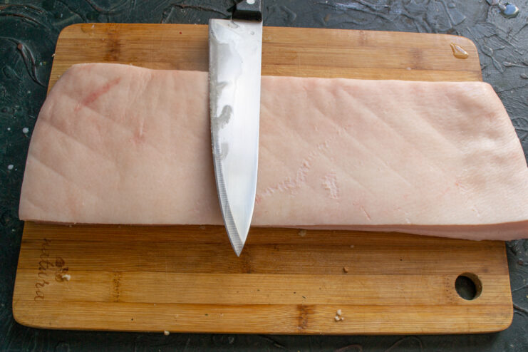 Scraping the skin Scraping the skin of a raw pork belly with a sharp chef's knife