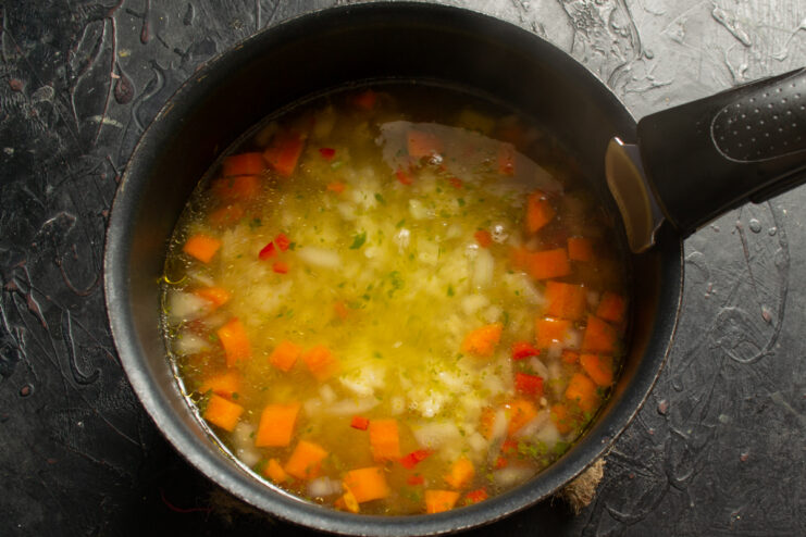 Simmering the soup over low heat Chicken soup with vegetables and rice simmering in a pot