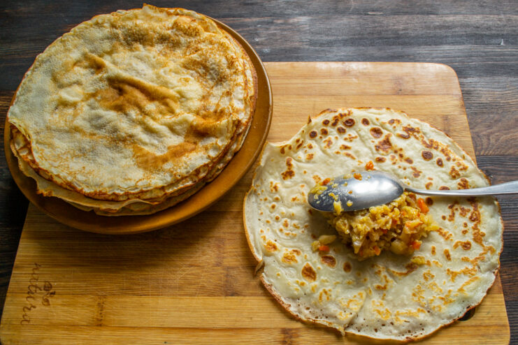 Stuffing the crepes Adding savory Savoy cabbage filling to the center of a crepe