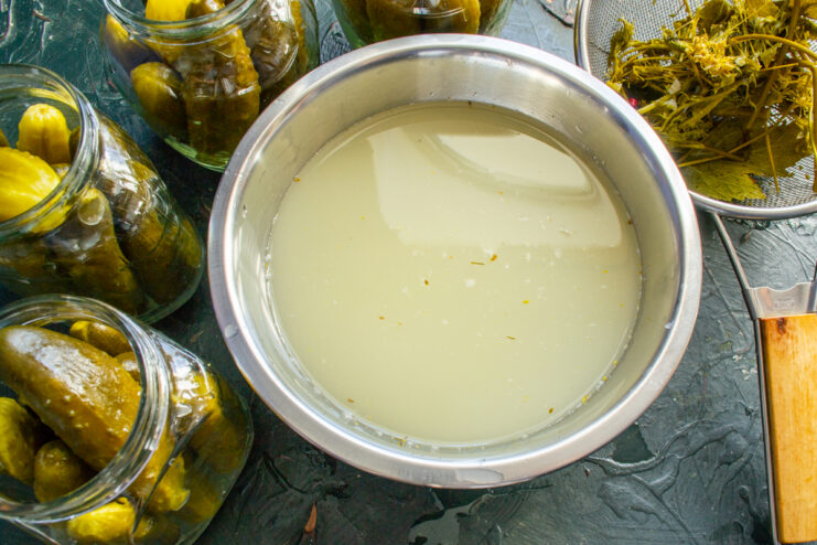 Strained pickle brine in a large metal bowl