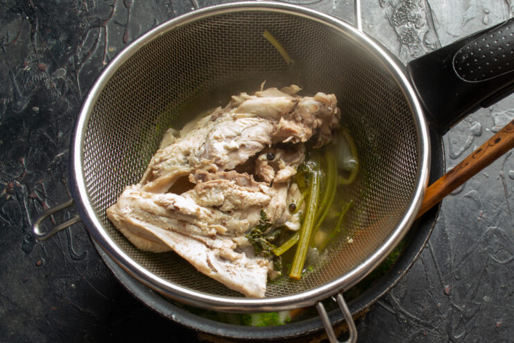 Straining the chicken broth Straining homemade chicken broth through a fine-mesh sieve into a pot