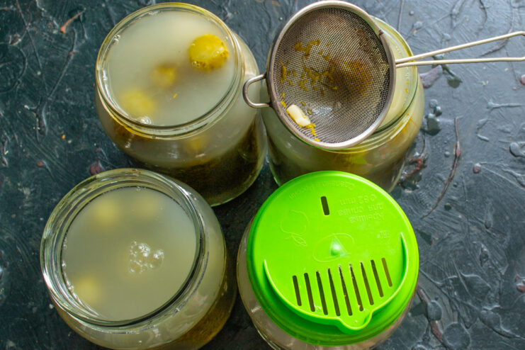 Straining the fermentation brine Straining murky pickle brine through a fine sieve into glass jars
