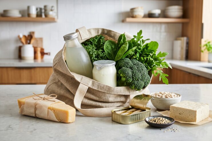 Shopping for Calcium-Rich Groceries Grocery basket filled with calcium-rich foods including kale, broccoli, yogurt, canned sardines, and packaged tofu.