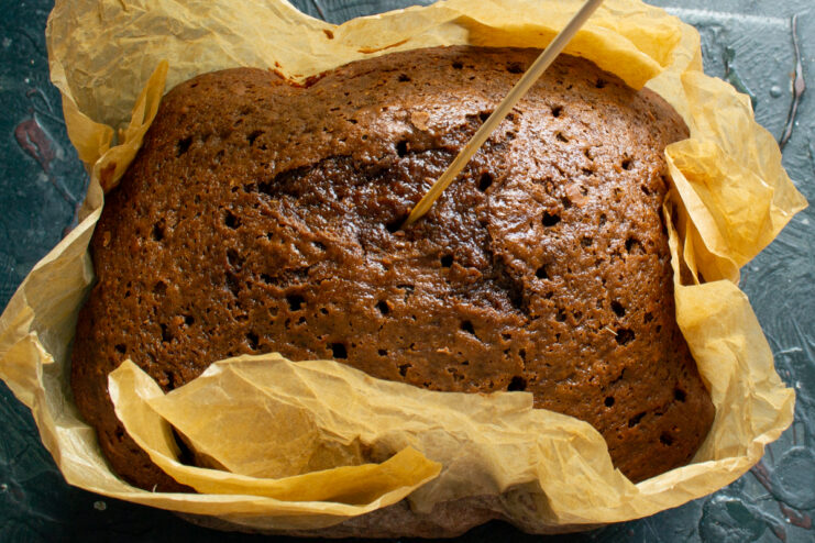 Prepping for syrup Piercing the warm chocolate sponge cake with a wooden skewer