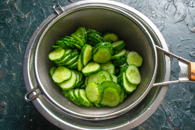 Rinsing Salt from Cucumbers Rinsed cucumber slices in a metal colander
