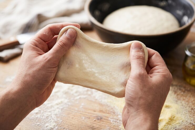 Windowpane Test for Dough Testing pizza dough elasticity using the windowpane method with both hands.