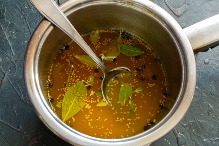 Making the Aromatic Brine Spiced brine with turmeric and bay leaves simmering in a saucepan