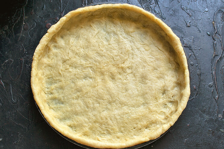 Rolling out the galette dough. Rolled out dough circle placed in a baking dish with slightly raised edges