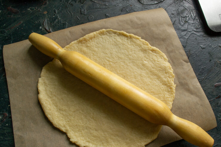 Rolling Out The Dough Rolling out a circle of dough with a rolling pin on parchment paper