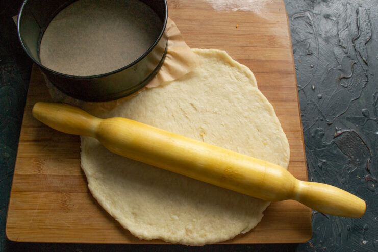 Rolling out the dough with a rolling pin on a wooden board