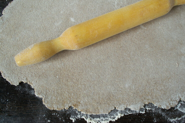 Rolling out the dough Rolling dough into a thin sheet using a wooden rolling pin