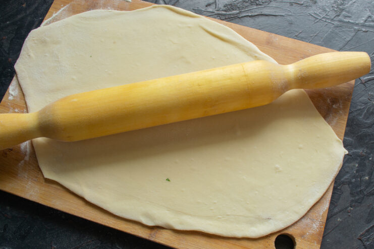 Rolling out a thin sheet of dough with a wooden rolling pin
