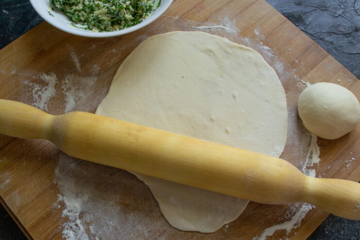 Rolling the Dough Rolling out a thin flatbread with a rolling pin on a wooden board