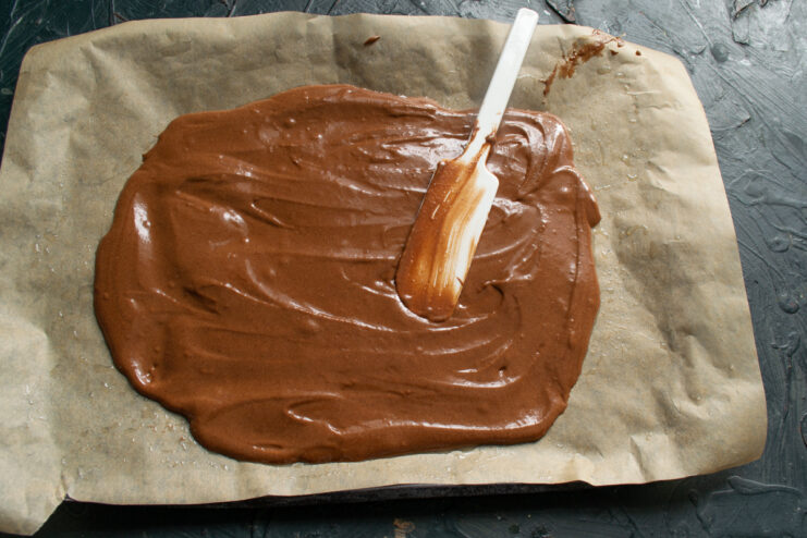 Spreading chocolate batter on a parchment-lined baking sheet.