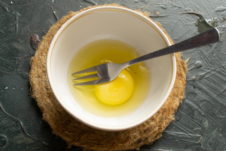 Whisking the Egg Cracked egg in a small bowl being whisked with a fork
