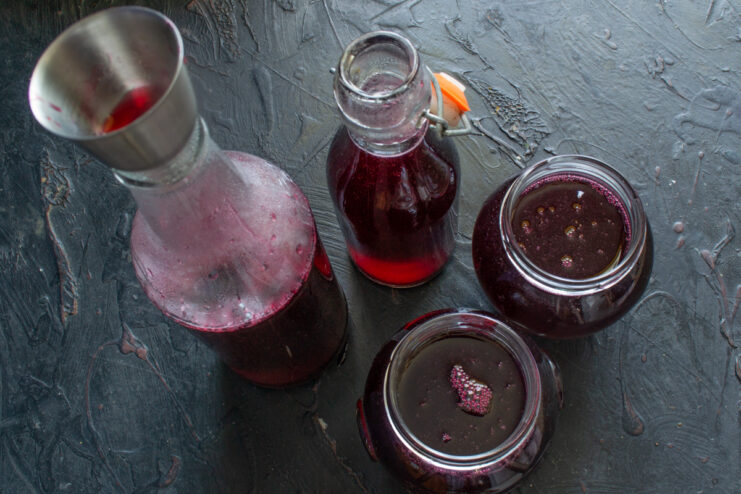 Bottling the finished syrup Pouring hot raspberry syrup into glass bottles