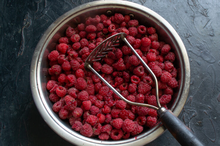 Mashing the raspberries Mashing raspberries with a metal potato masher in a pot