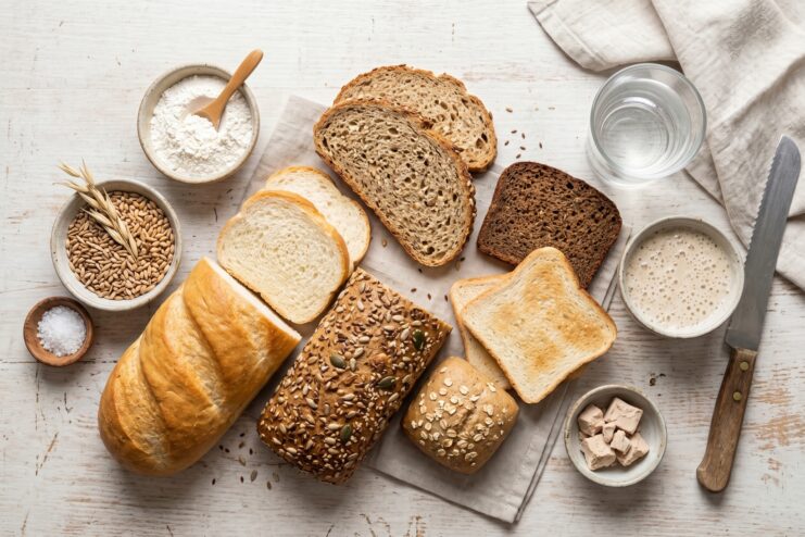 Various Types Of Bread For A Child's Diet Assortment of baked goods including white loaf, rye, whole grain, and sliced toasting bread on a wooden table.