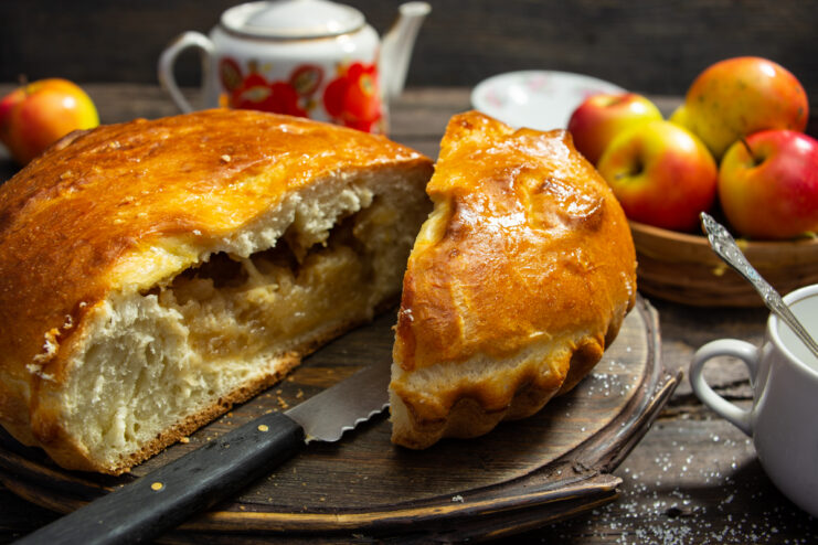 Sliced homemade apple jam pie on a wooden board