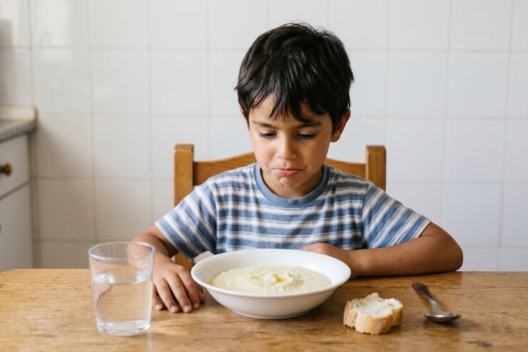 Bland Semolina As A Spanish Dietetic Dish Child looking down at a plain bowl of water-boiled semolina porridge