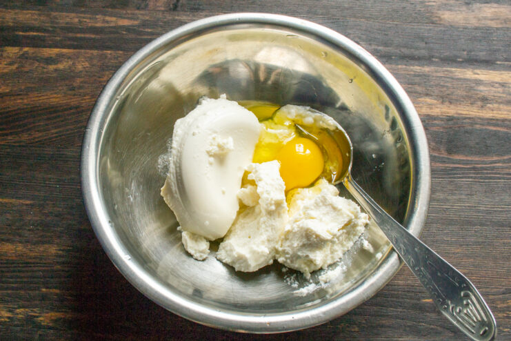 Mixing the cheese base Ricotta cheese and an egg mixed in a glass bowl