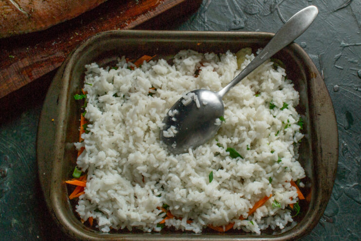 Layering the Parboiled Rice Partially cooked rice spread over the vegetable layer in a baking dish