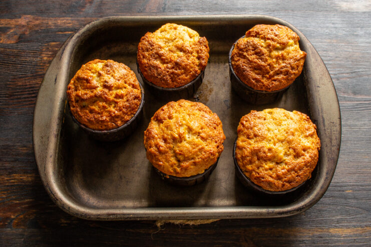 Checking muffins for doneness Freshly baked golden muffins in paper liners resting on a baking tray.