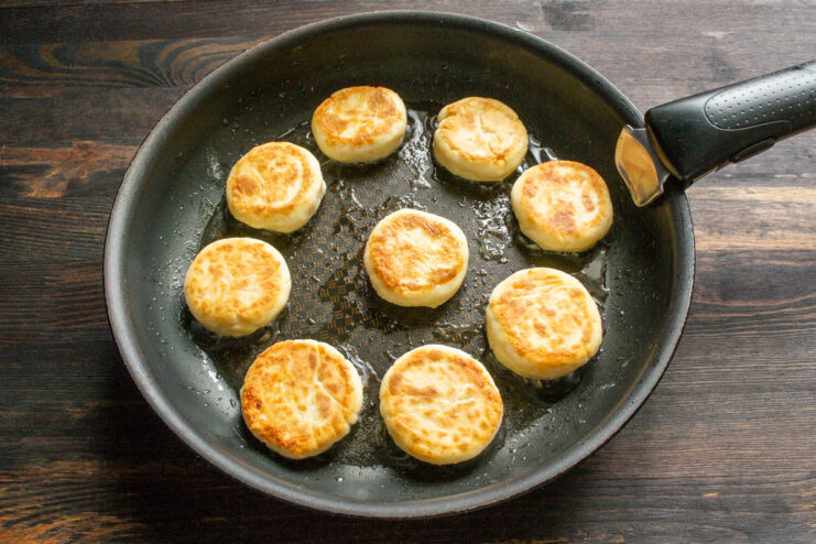 Flipping for a golden crust Golden brown syrniki flipped over in a hot skillet