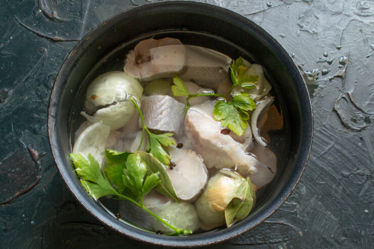 Ingredients for the Fish Broth Fish, onion, and parsley submerged in a pot of water