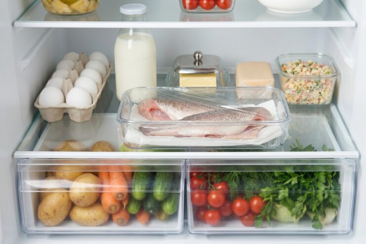 Fresh Fish Storage Guidelines A raw fish fillet stored inside a glass container resting on a refrigerator shelf