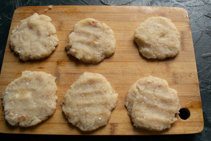 Shaping the Patties Shaped flat minced fish patties on a wooden cutting board