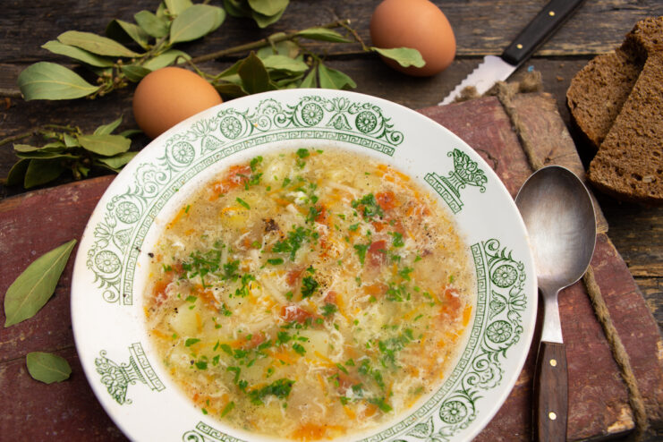 Fish soup with egg and zucchini served in a bowl with bread and herbs