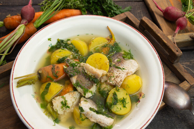 Fish soup with spinach, new potatoes, and carrots served in a deep bowl
