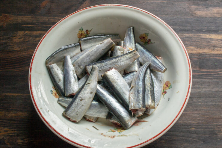 Removing the fish heads Headless Baltic herring in an enamel bowl