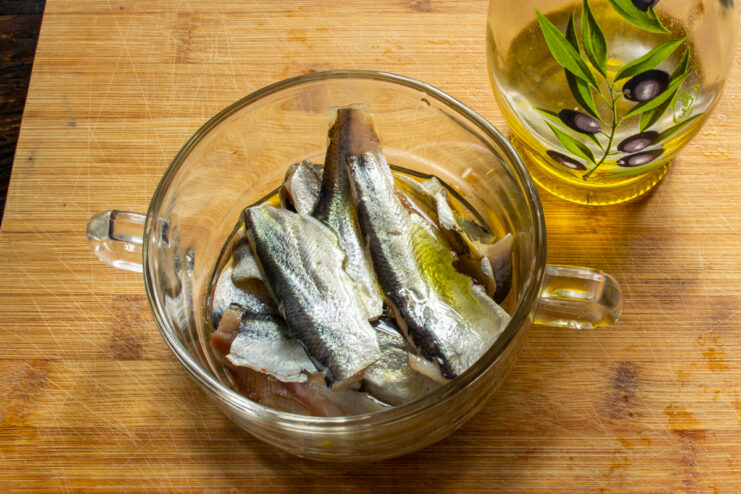Marinating the herring in olive oil Salted Baltic herring submerged in olive oil in a bowl