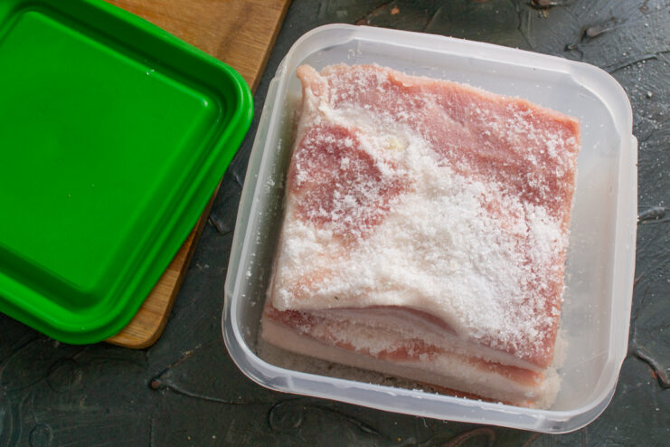 Salo covered in salt Raw pork fat completely buried in coarse salt inside a sealed container